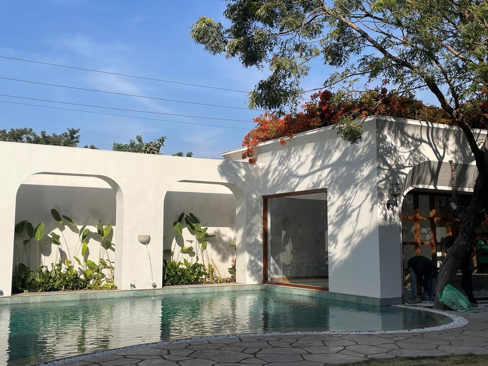 The pool beside the white arches of the house